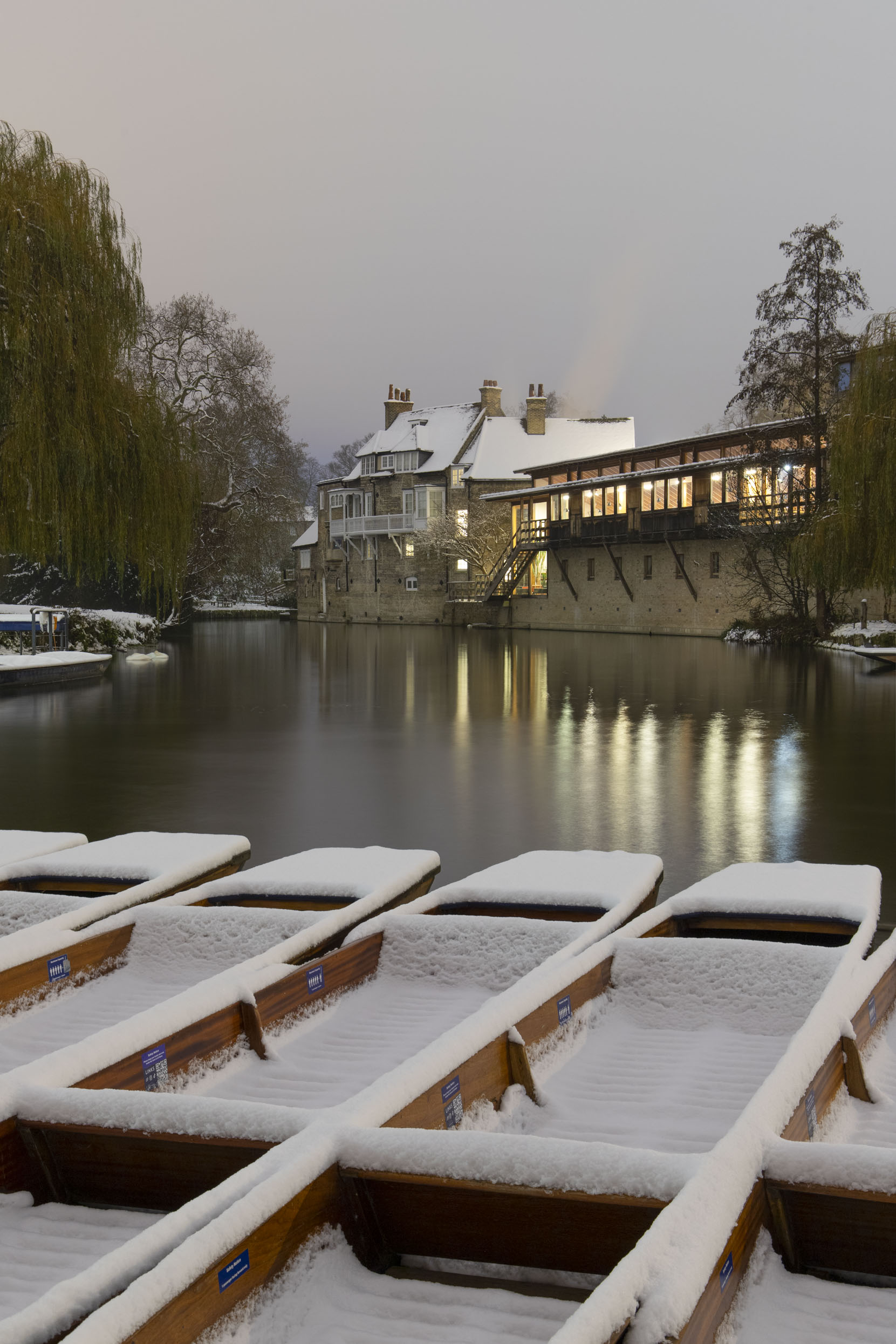A rare snowy day in Cambridge in December 2022. Darwin college seen behind the Scudamore punts.